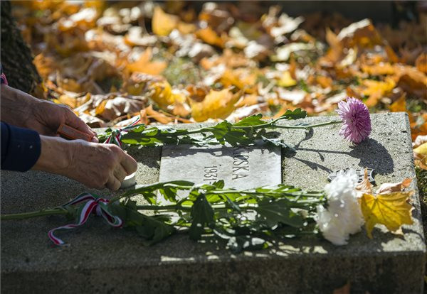 Fotó: MTI / Mohai Balázs Egy megemlékező mécsest gyújt egy síremléknél a Rákoskeresztúri új köztemető 301-es parcellájában