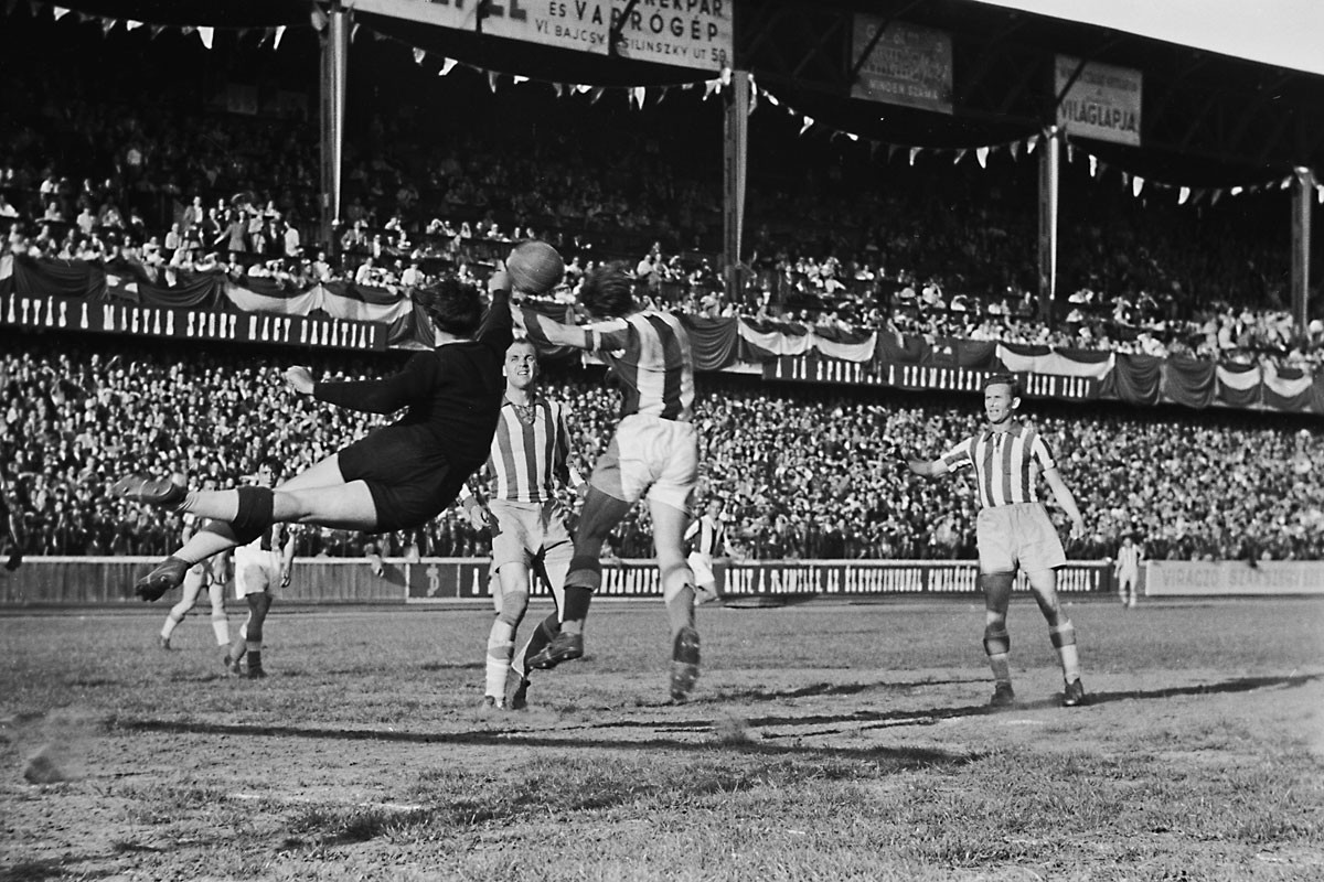 Fradi–Újpest rangadó (4:3) az Üllői úton, 1949-ben. Két évvel később a vetődő Henni Géza kényszerből már a lila-fehéreket szolgálta mint a Bp. Dózsa kapusa, Csanádi Árpád (középen) és Lakat Károly (jobbra) pedig az ÉDOSZ játékosa volt