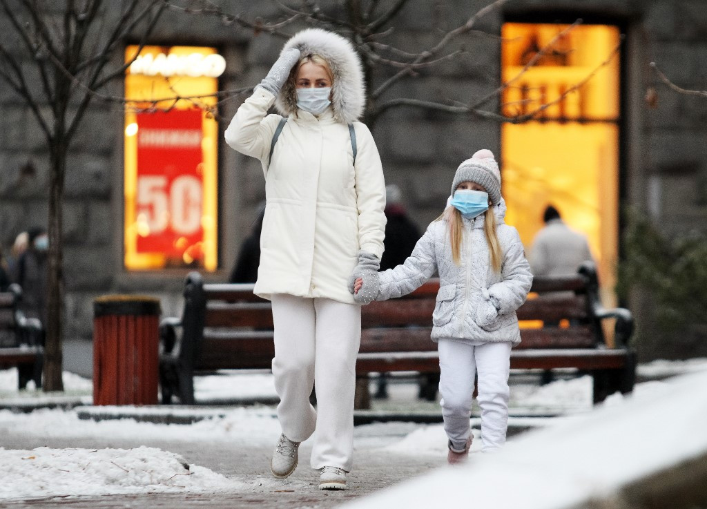 Arcmaszkot viselő járókelők Kijevben