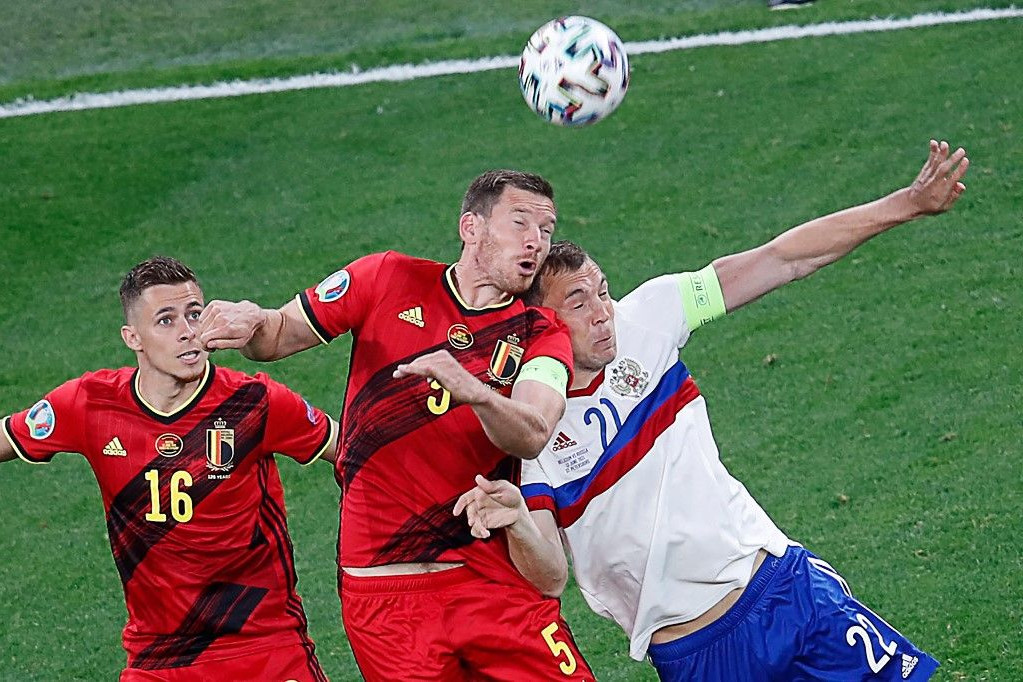 A belga középpályás, Thorgan Hazard és a belga védő, Jan Vertonghen harcol a labdáért az orosz támadóval, Artem Dzyubával