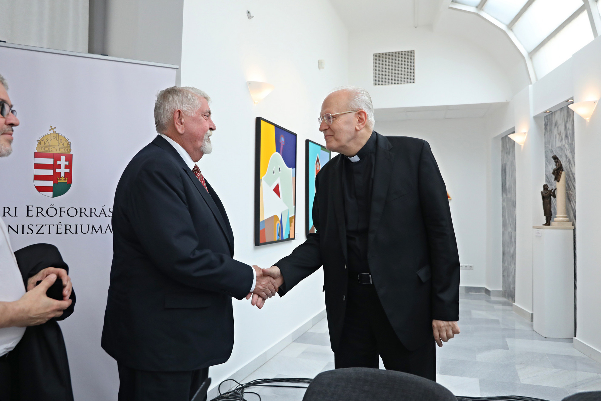 Kásler Miklós (balra) emberierőforrás-miniszter kezet fog Erdő Péter bíborossal a kiállítás megnyitóján
