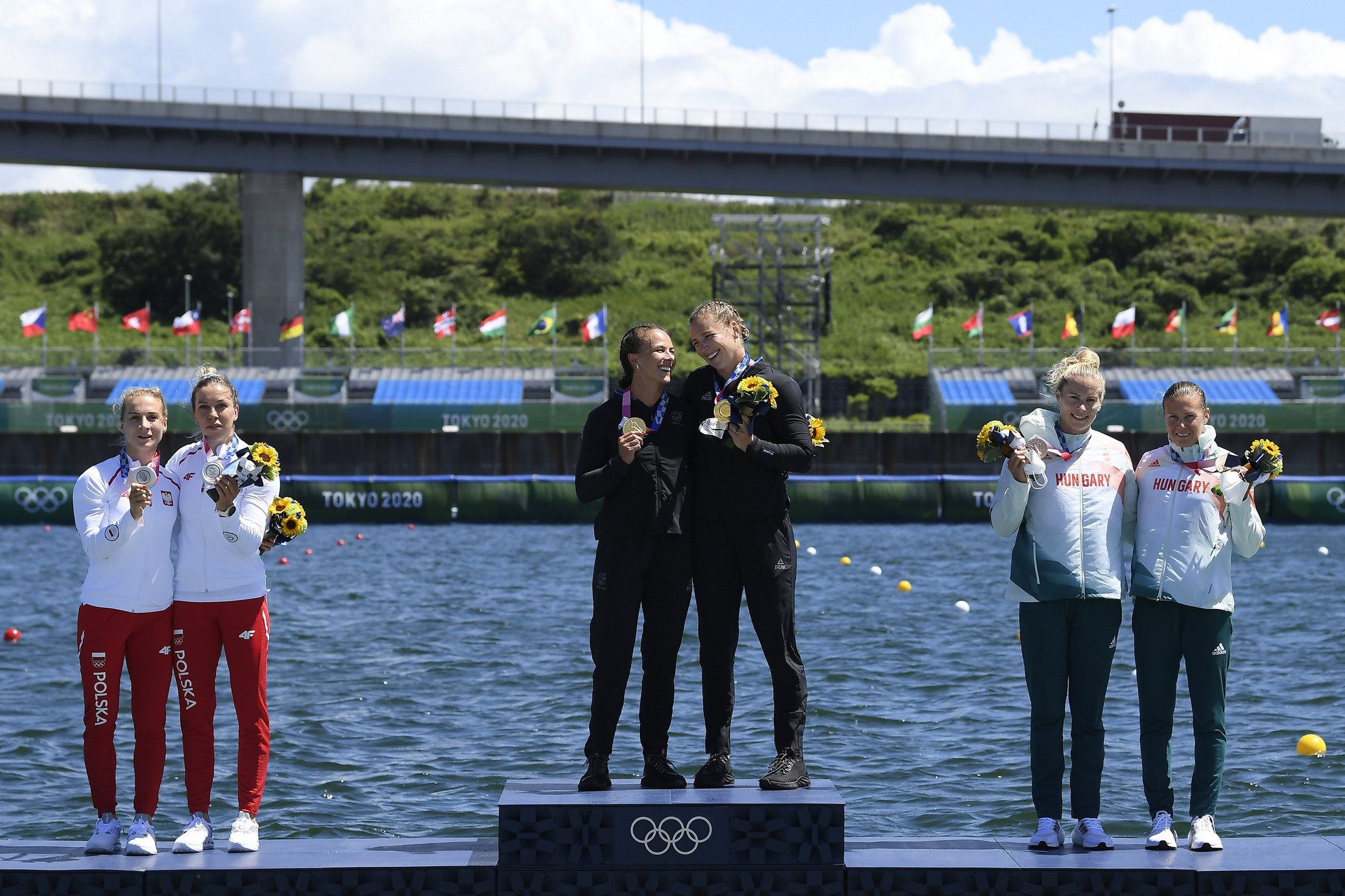 A győztes új-zélandi Lisa Carrington Lisa, Caitlin Regal (középen), a második helyezett lengyel Anna Pulawska és Karolina Naja (b), jobbról a bronzérmes Bodonyi Dóra (b) és Kozák Danuta a női kajak párosok 500 méteres versenyének eredményhirdetésén a világméretű koronavírus-járvány miatt 2021-re halasztott 2020-as tokiói nyári olimpián a Sea Forest Kajak-kenu Pályán 2021. augusztus 3-án