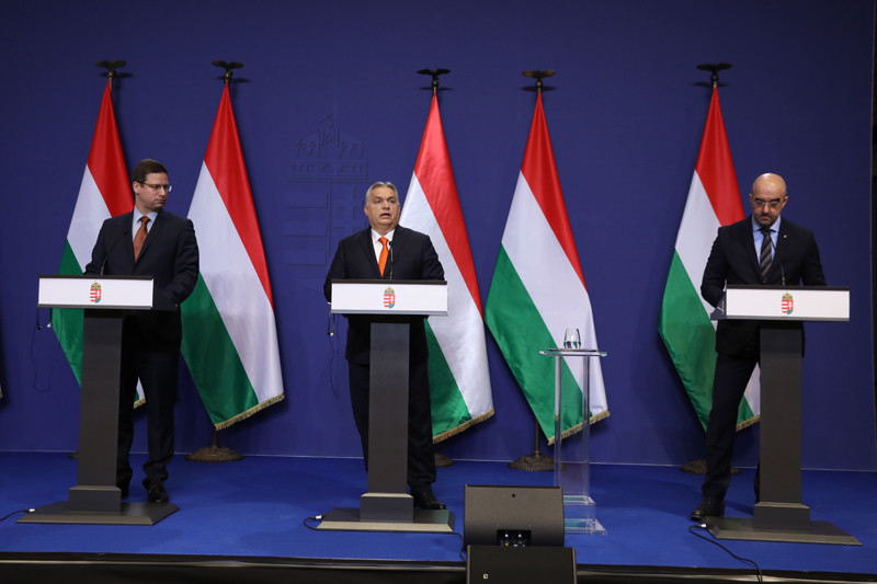 Orbán Viktor miniszterelnök (k), mellette Gulyás Gergely, a Miniszterelnökséget vezető miniszter (b) és Kovács Zoltán, a Miniszterelnöki Kabinetiroda nemzetközi kommunikációért és kapcsolatokért felelős államtitkára (j) a Kormányinfó sajtótájékoztatón a Karmelita kolostorban 2021. december 21-én