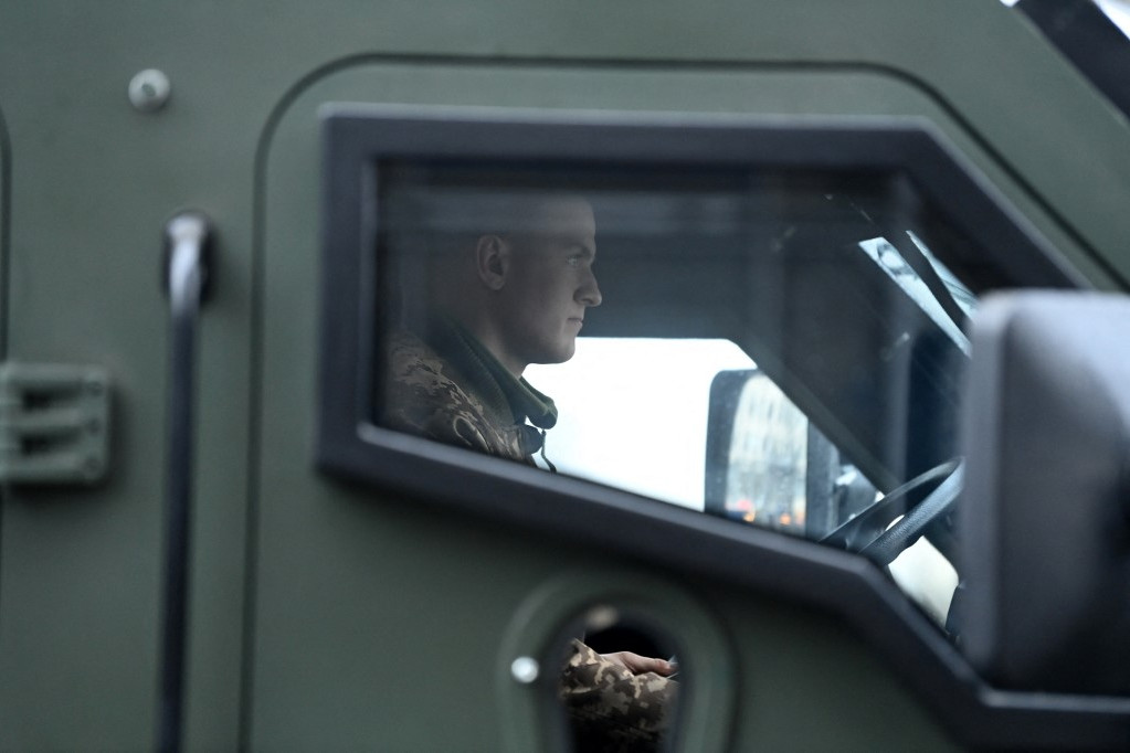 Ukrán pácélozott teherautót vezet egy katona Kijevben