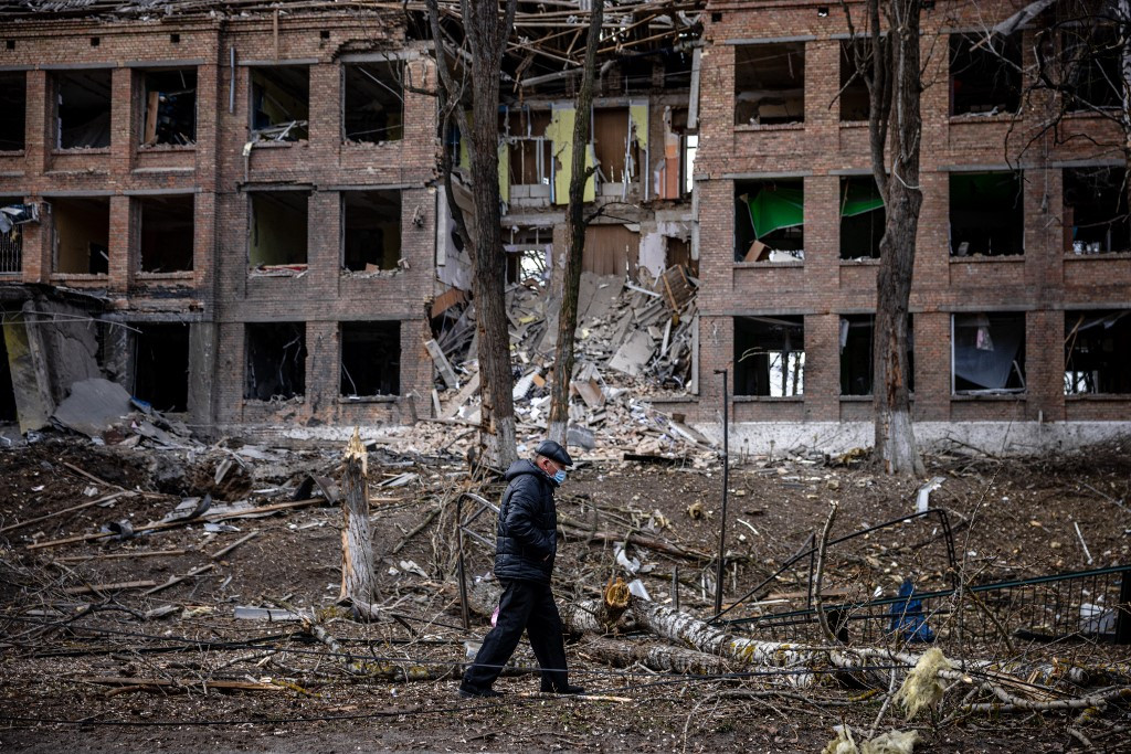 Egy Kijev közelében található épület romjai előtt sétál egy idősebb ukrán férfi