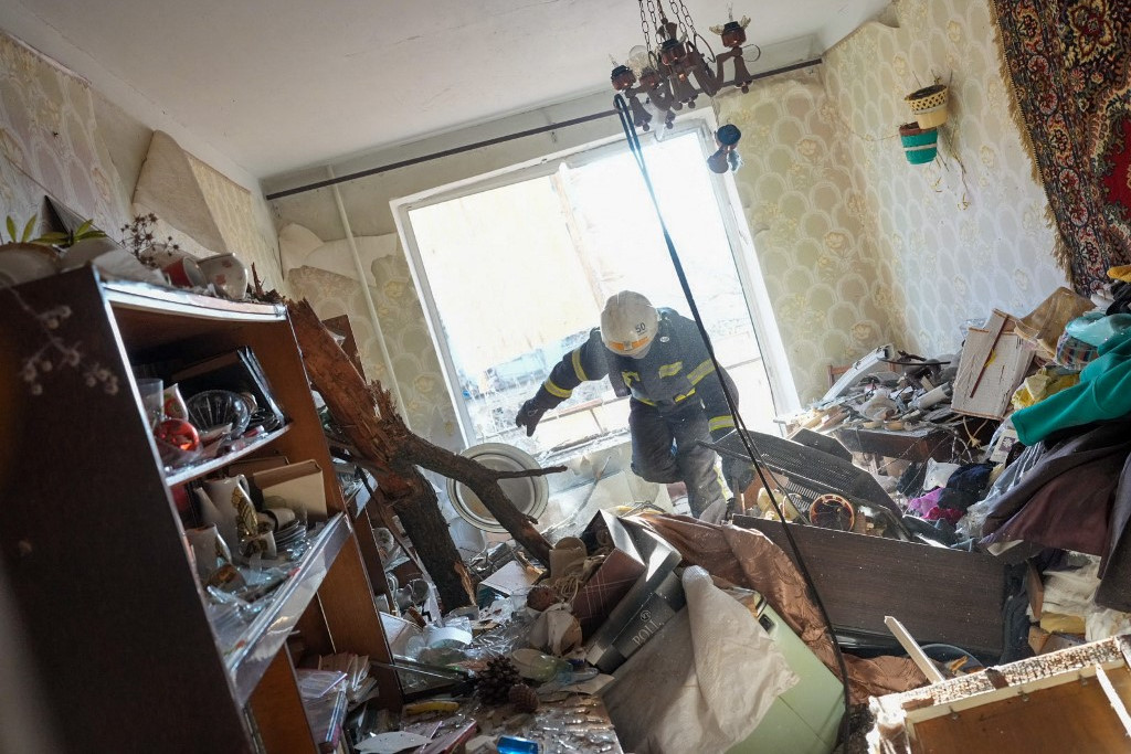 Tűzoltó próbál bejutni egy bombatámadás érte házba Csuhuivban