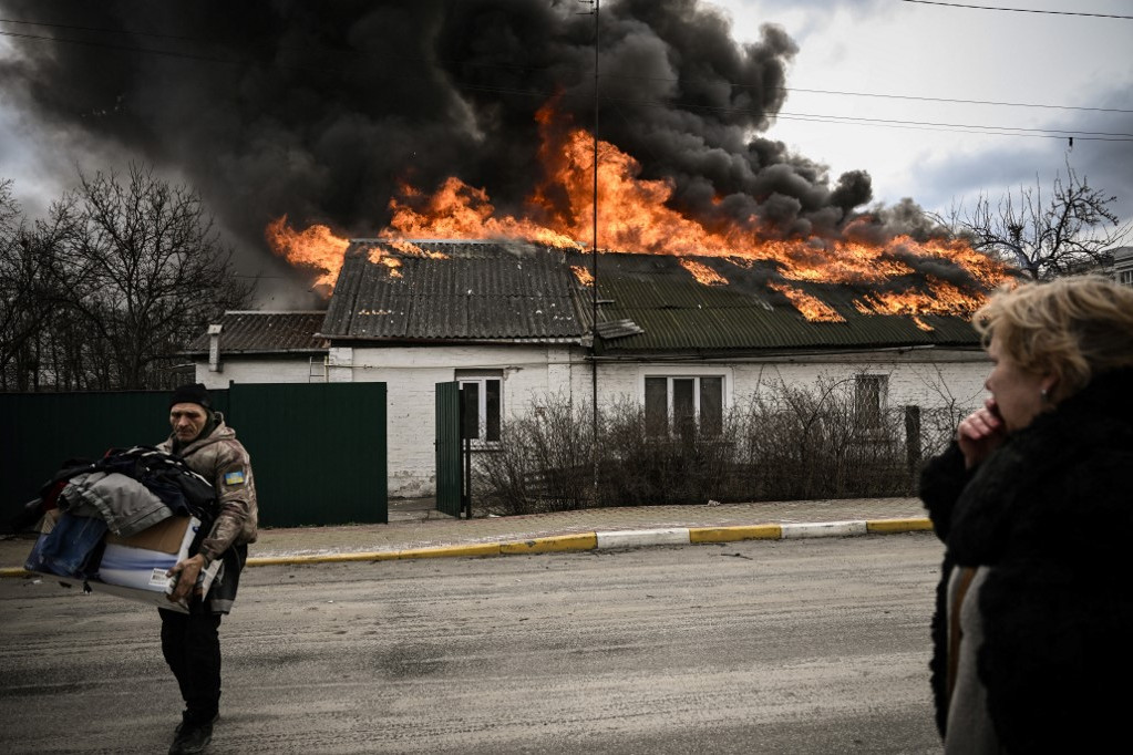 Egy ukrán férfi néhány személyes holmiját menti ki lángoló otthonából, Kijev külső részén