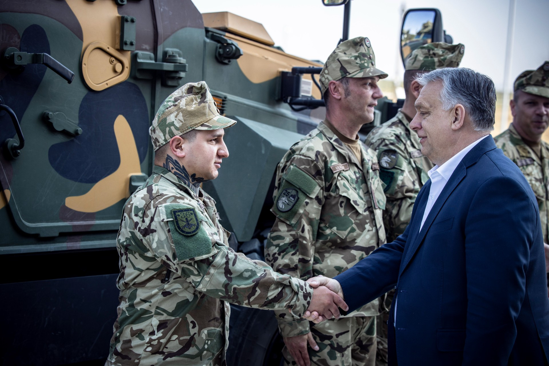 Orbán Viktor miniszterelnök (j2) kezet fog egy katonával a zalaegerszegi Lynx harcjárműgyár épületének és elkészült moduljainak ünnepélyes átadóján