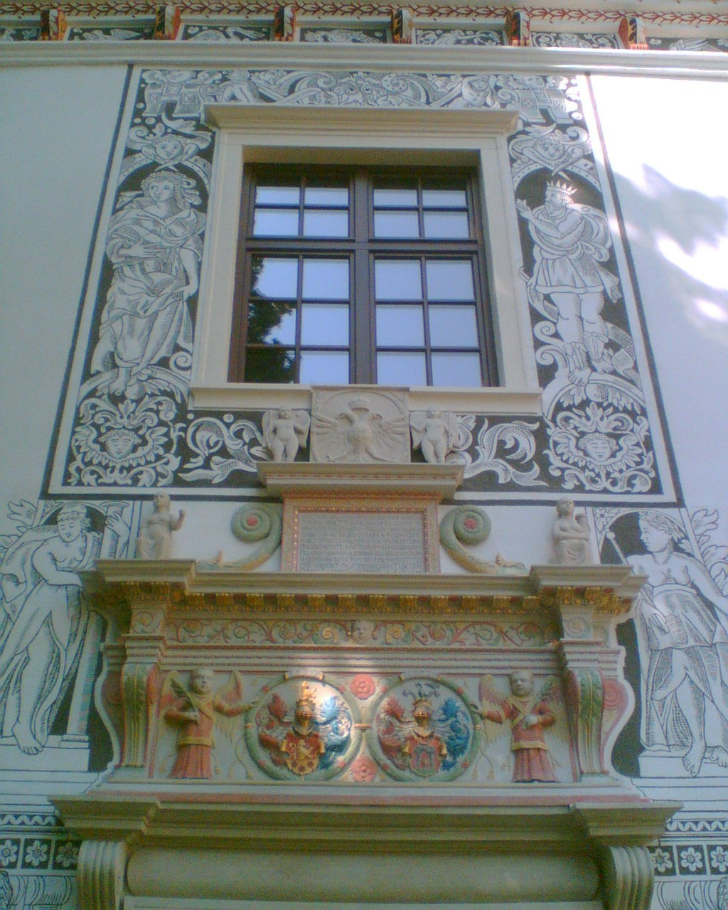 Sgrafittós ablak, emléktábla és címerek a főbejárat felett