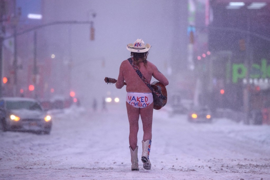 Egy alsónadrágos cowboy zenél a hóviharban a new york-i Times Square-en 2022. január 29-én. Az alsónadrágján a meztelen cowboy felirat olvasható. A vihar rengeteg havat és erőteljes szelet zúdított az Egyesült Államok keleti partjára