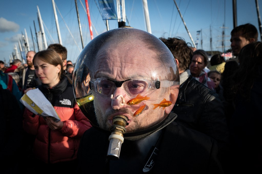 Egy férfi különös „fejfedője” vízzel teli akváriummal és aranyhalakkal Saint-Malo faluban, a Route du Rhum szólóvitorlás verseny kiindulópontján, Franciaországban 2022. november 1-jén.