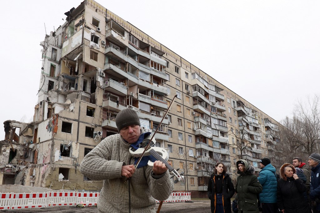 Egy férfi hegedül a helyi lakosok által tartott istentiszteleten az ukrán Dnyipro városában egy rakétatámadás következtében megsemmisült lakóház előtt. A halálos áldozatok száma a január 14-i támadást követően már 45-re nőtt, így ez a csapás volt az egyik legsúlyosabb azóta, hogy Oroszország megtámadta Ukrajnát, de a Kreml tagadja a felelősségét. (2023. január 22.)