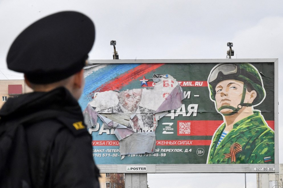 Egy kiskadét a szerződéses katonai szolgálatot hirdető plakát előtt Szentpéterváron. Vlagyimir Putyin orosz elnök szeptember 21-én bejelentette, hogy oroszok százezreit mozgósítják Moszkva ukrajnai hadseregének megerősítésére. (2022. október 5.)