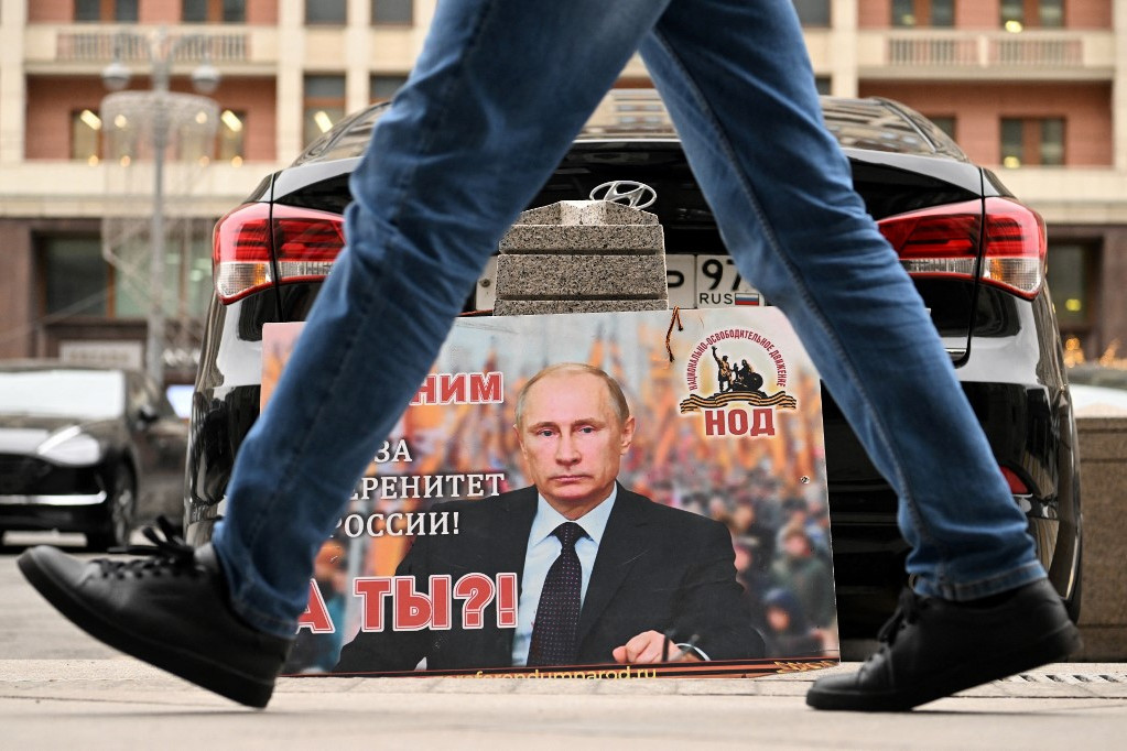 Egy plakát az orosz Állami Duma épülete előtt Moszkvában Vlagyimir Putyin képével és a következő szöveggel: „Mi vele vagyunk Oroszország szuverenitásáért! És te?” (2022. február 24.)