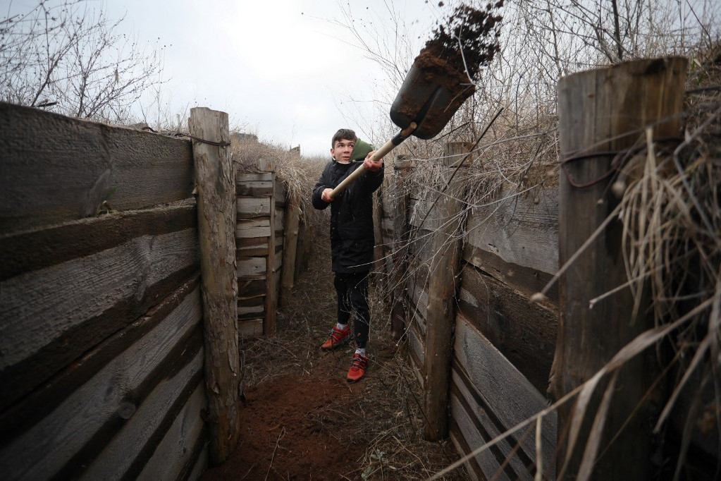 Egy ukrán tinédzser ássa az árkot az ország keleti frontján szolgáló és az oroszok által támogatott szakadárokkal szemben álló katonák számára a kelet-ukrajnai Cservone falu közelében, Mariupol régióban. (2022. február 11.)