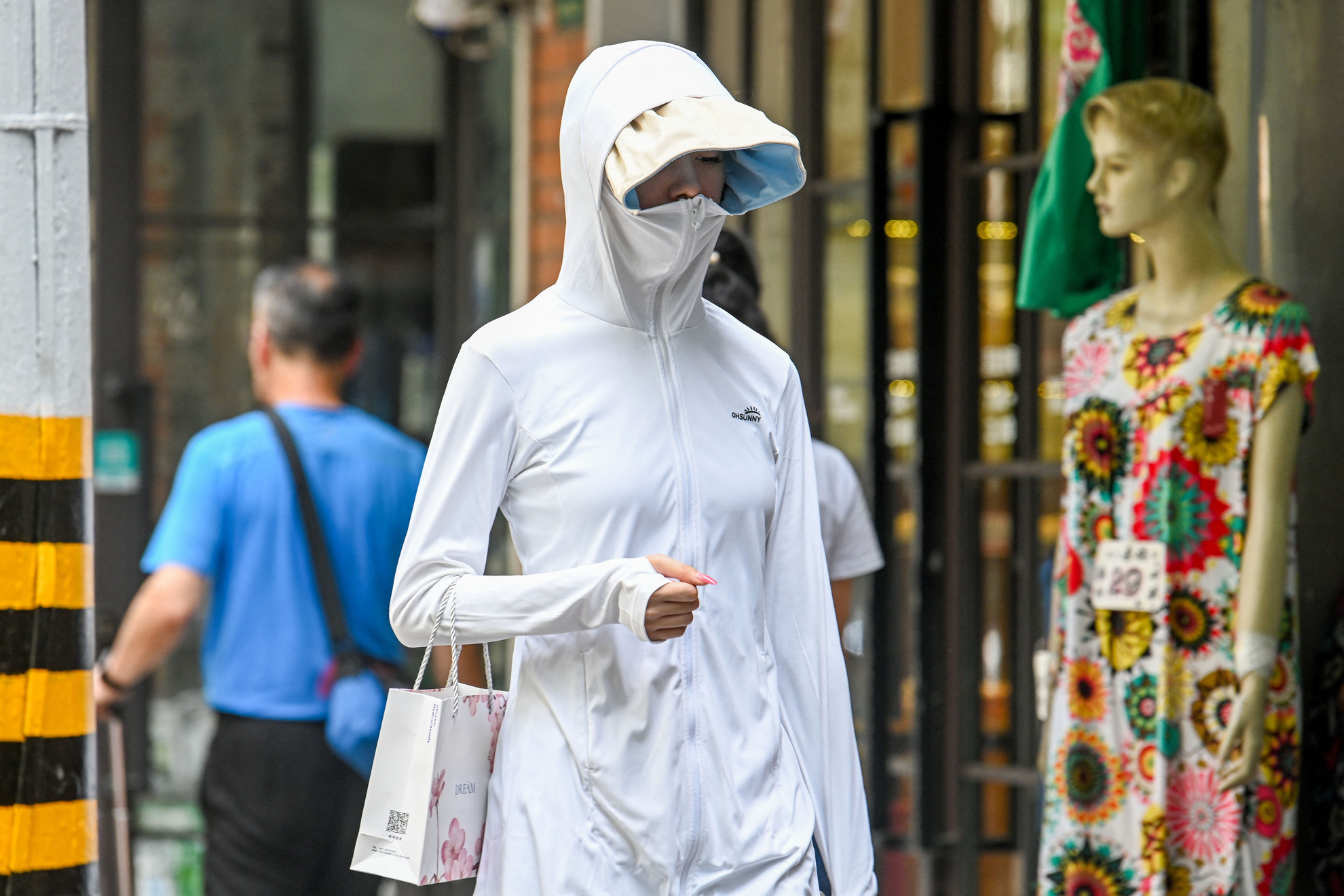 Teljes testet fedő, kapucnis, napellenzős ruhát hordanak a rekkenő hőségben Kínában, hogy védjék bőrüket a napsugarak káros hatásai ellen 2023. május 29-én. Százéves melegrekordot mértek Sanghajban. A délutáni órákban a hőmérő higanyszála elérte a 36,7 Celsius-fokot.