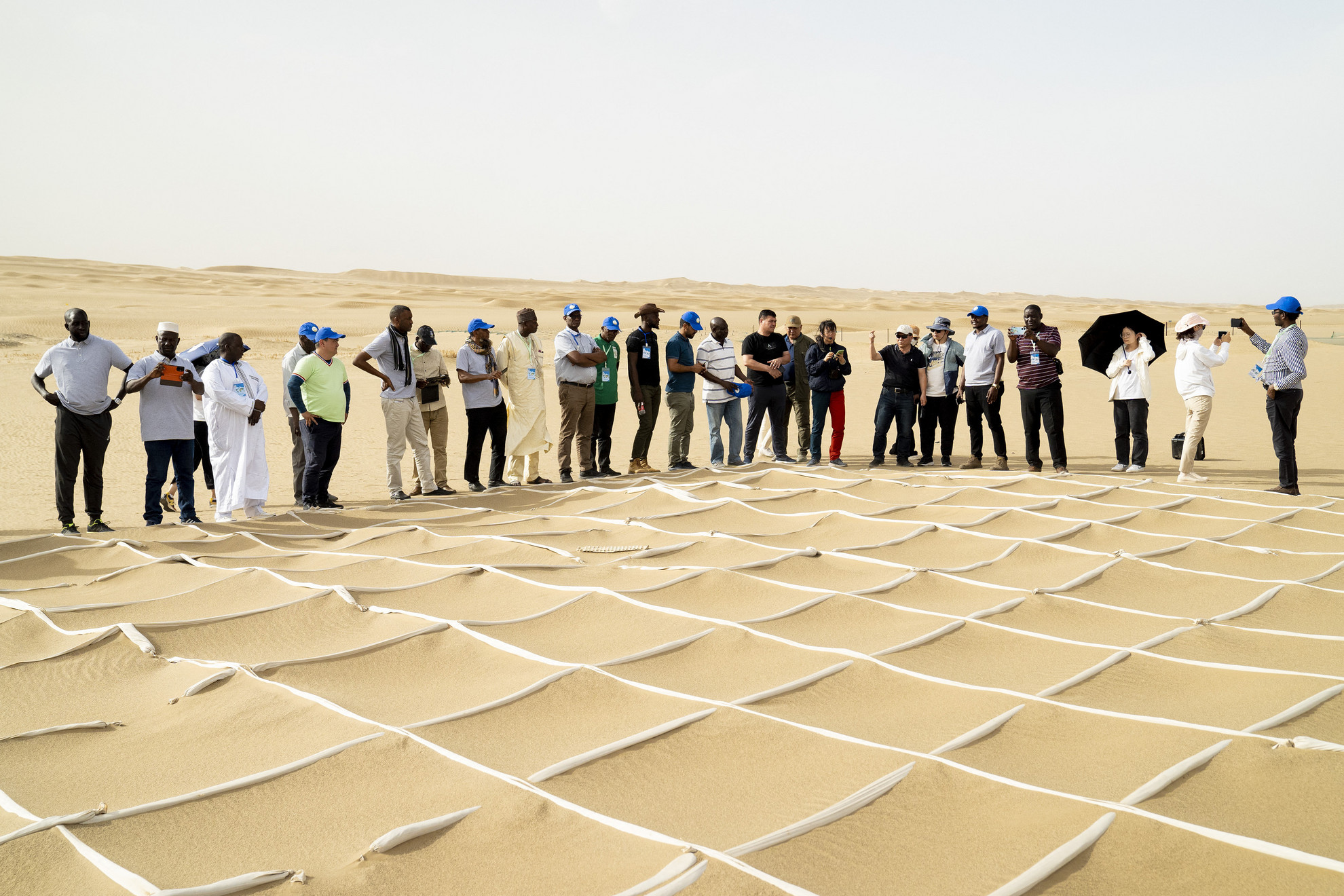 Az elsivatagosodás elleni küzdelemmel foglalkozó képzésen homokfixáló technológiákkal ismerkednek egy homokvihar megelőzési bemutatóhelyen a Taklimakan sivatagban, Kína északnyugati részén, 2023. június 12-én.