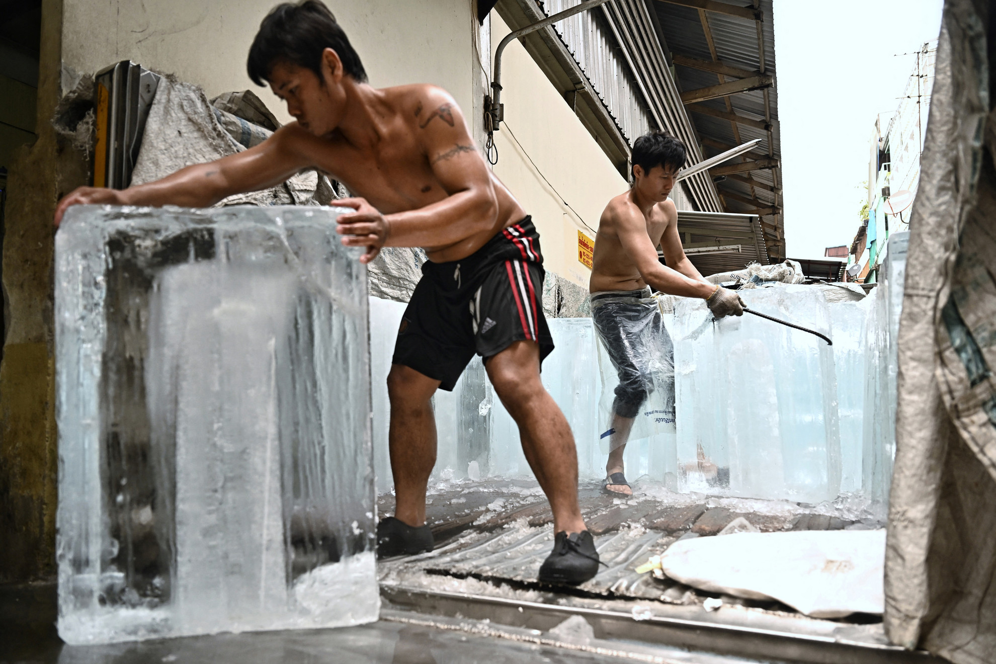 Jégtömböket szállítanak egy tárolóegységbe egy piacon a hőhullám idején Bangkokban, 2023. április 25-én. A tudósok szerint a globális felmelegedés súlyosbítja a kedvezőtlen időjárási viszonyokat. Az elmúlt hetekben számos országban halálos kánikulát és rekordokat döntögető hőmérsékletet tapasztaltak Délkelet- és Dél-Ázsiában. Májusban az ENSZ arra figyelmeztetett, hogy 2023-2027 között szinte biztos, hogy a valaha feljegyzett legmelegebb ötéves időszaka következik, mivel az üvegházhatású gázok és az El Nino együttesen a hőmérsékletet a magasba repítik.