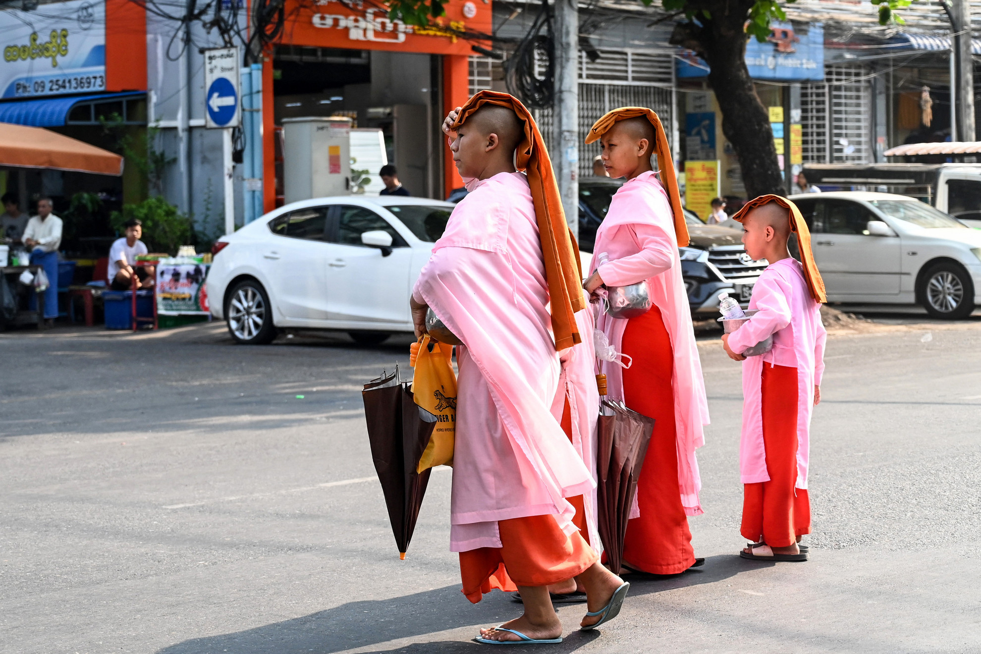 Buddhista szerzetesek fedett fejjel sétálnak, hogy védekezzenek a nap elől a hőhullám alatt Yangonban 2023. április 24-én.