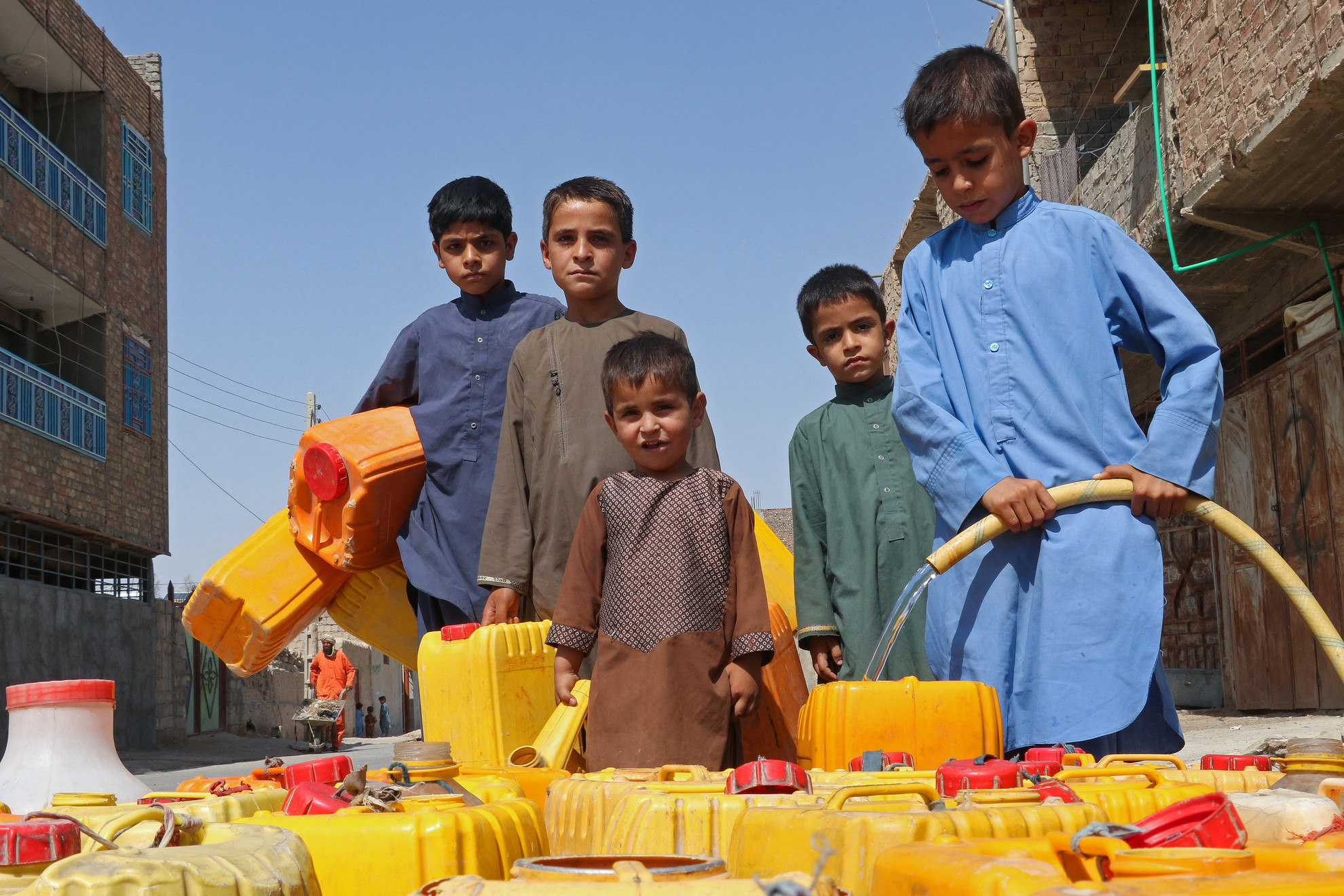 Afgán fiúk kannákat töltenek ivóvízzel Farah városában 2023. június 20-án
