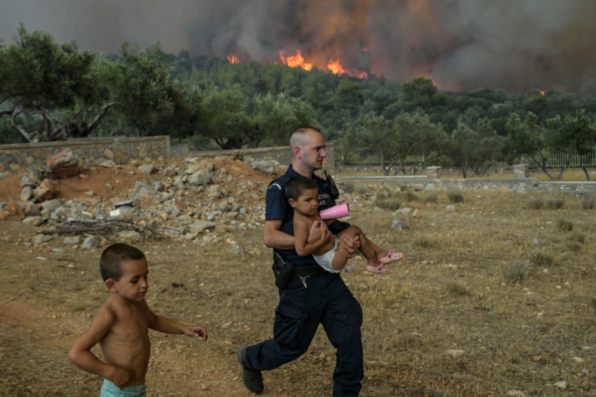 Fotó: Aris MESSINIS / AFP Egy görög rendőr gyermekeket evakuál Agios Charamlabos faluból 2023. július 18-án