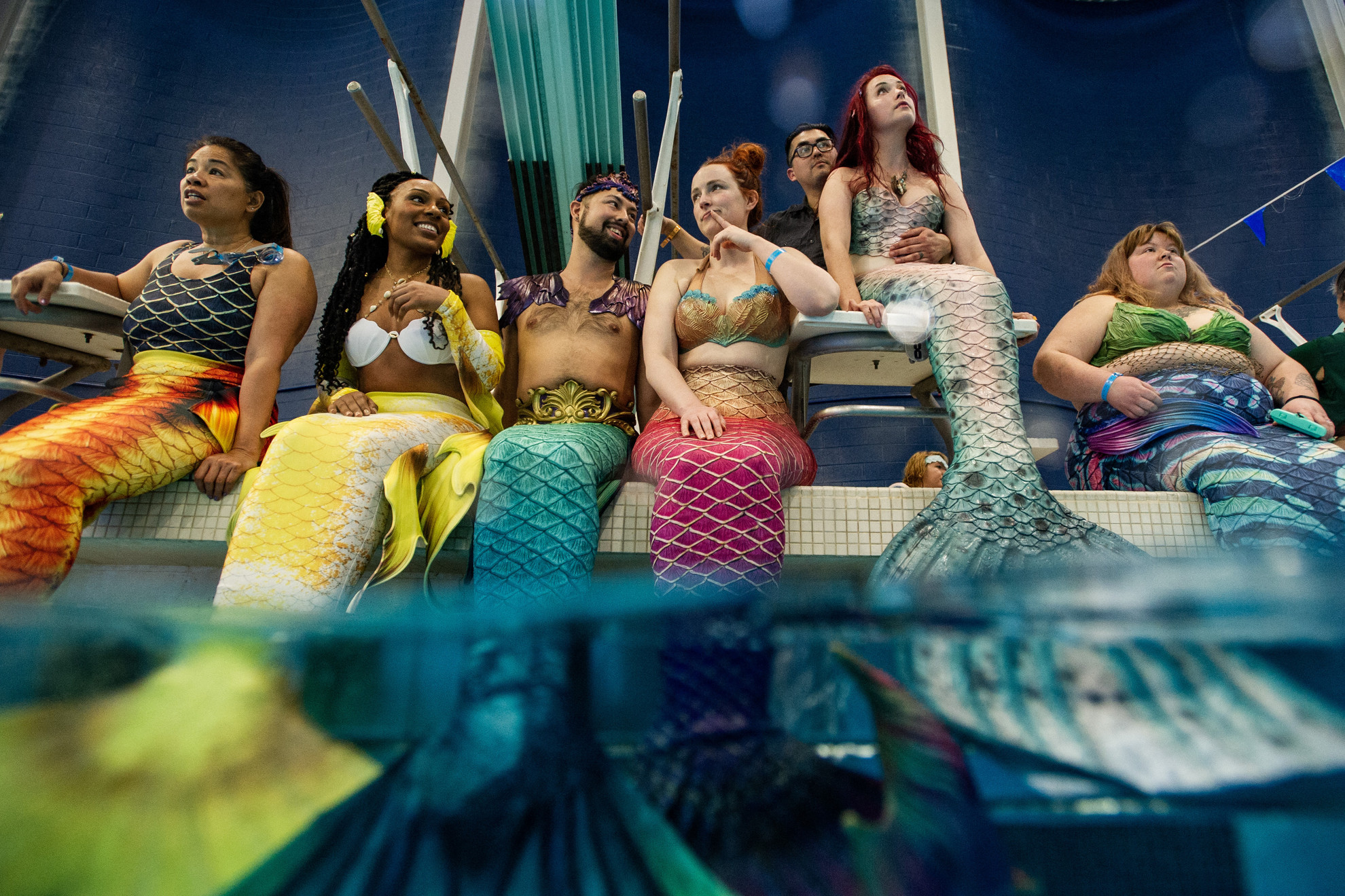 Fotó: AFP/Joseph Prezioso A 33 éves Helena McLeod (jobbról a második, háta mögött a férje) és sellő társai a MerMagic kongresszuson a Freedom Aquatic & Fitness Centerben a virginiai Manassasban 2023. március 4-én. Helena CMT (charcot-marie-tooth) betegségben szenved, ezért kerekesszékhez van kötve, de még mindig részt vesz a sellőéletben