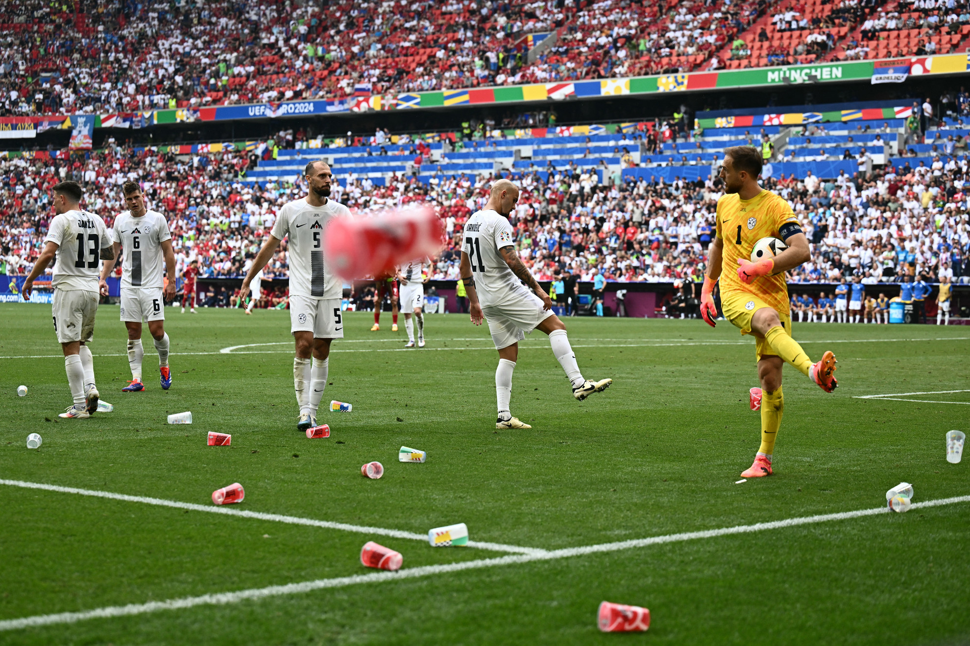 A szlovén játékosok rugdossák a pályára dobott söröspoharakat az UEFA Euro 2024 C csoportjának Szlovénia-Szerbia mérkőzésén a müncheni futballarénában 2024. június 20-án