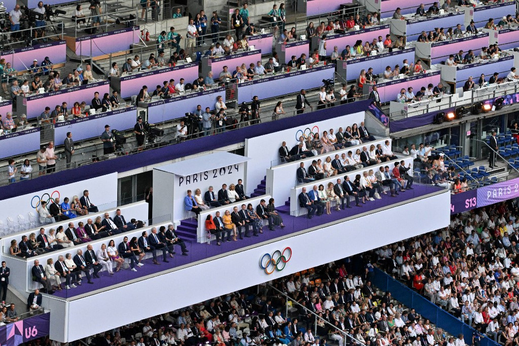 Emmanuel Macron francia elnök (k.) felesége, Brigitte Macron (k. j.), Thomas Bach, a Nemzetközi Olimpiai Bizottság (NOB) elnöke (k. b.) és Tony Estanguet, a Párizs 2024 olimpiai és paralimpiai játékok szervezőbizottságának elnöke (j.), tisztviselők és nézők a Párizs 2024 olimpiai játékok záróünnepségén a Stade de France stadionba