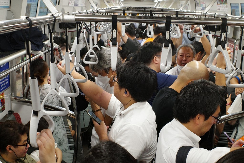 Utasok egy JR Japan Rail metróban a városközpontban, csúcsforgalomban.