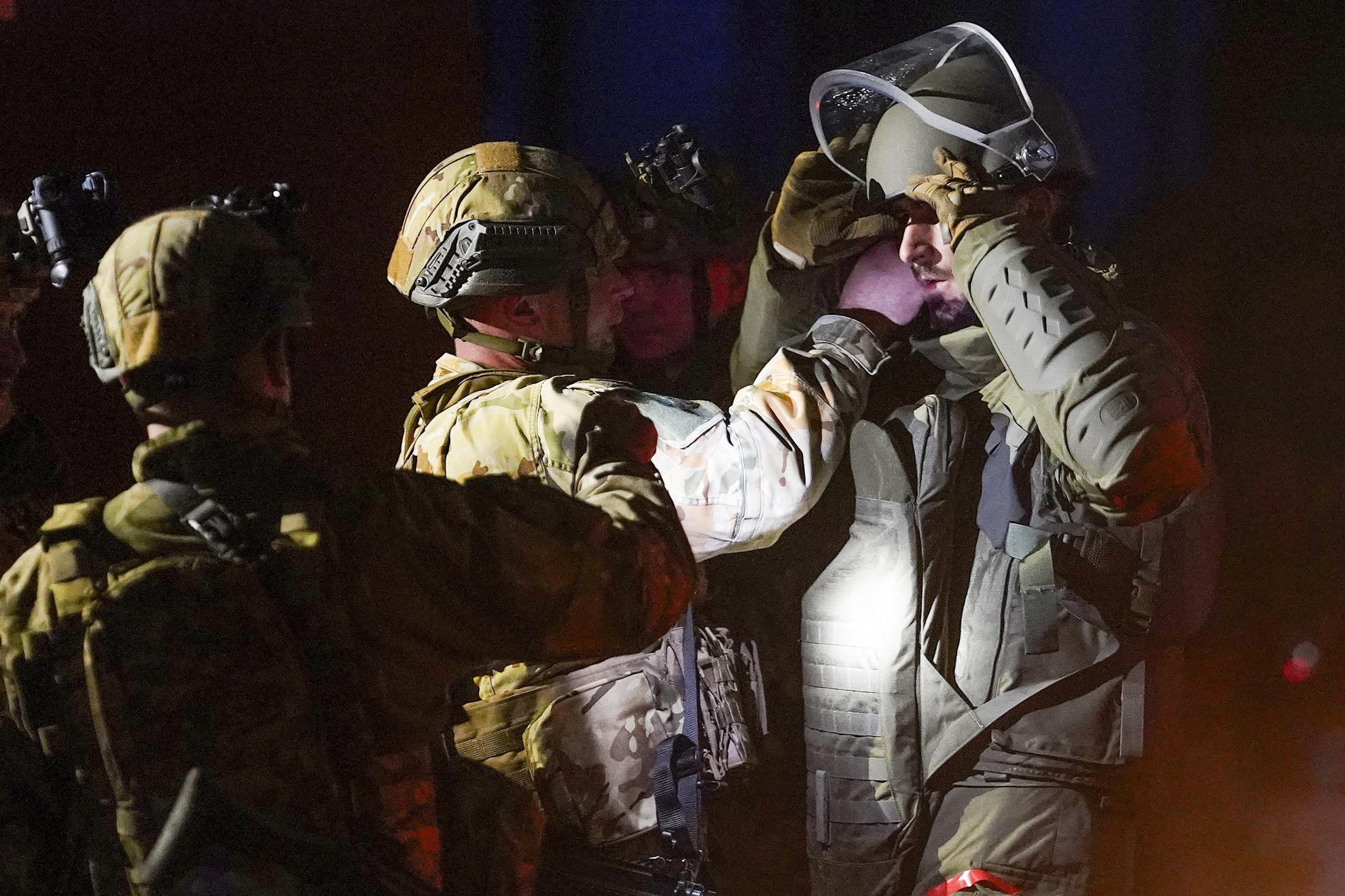 THC 6 moduláris tűzszerész-védőruhába öltöztetnek egy katonát (j) az MH 1. Tűzszerész és Folyamőr Ezred éjszakai gyakorlatán, amelyen tűzszerészek improvizált robbanóeszközök hatástalanítását végzik egy fiktív merénylet után, speciális körülmények között az újdörögdi gyakorlótéren 2024. október 17-én. A tűzszerészek egy szórakozóhelyen elkövetett, szimulált merénylet után avatkoztak be, felderítettek, majd ártalmatlanítottak különféle házilag gyártott robbanóeszközöket
