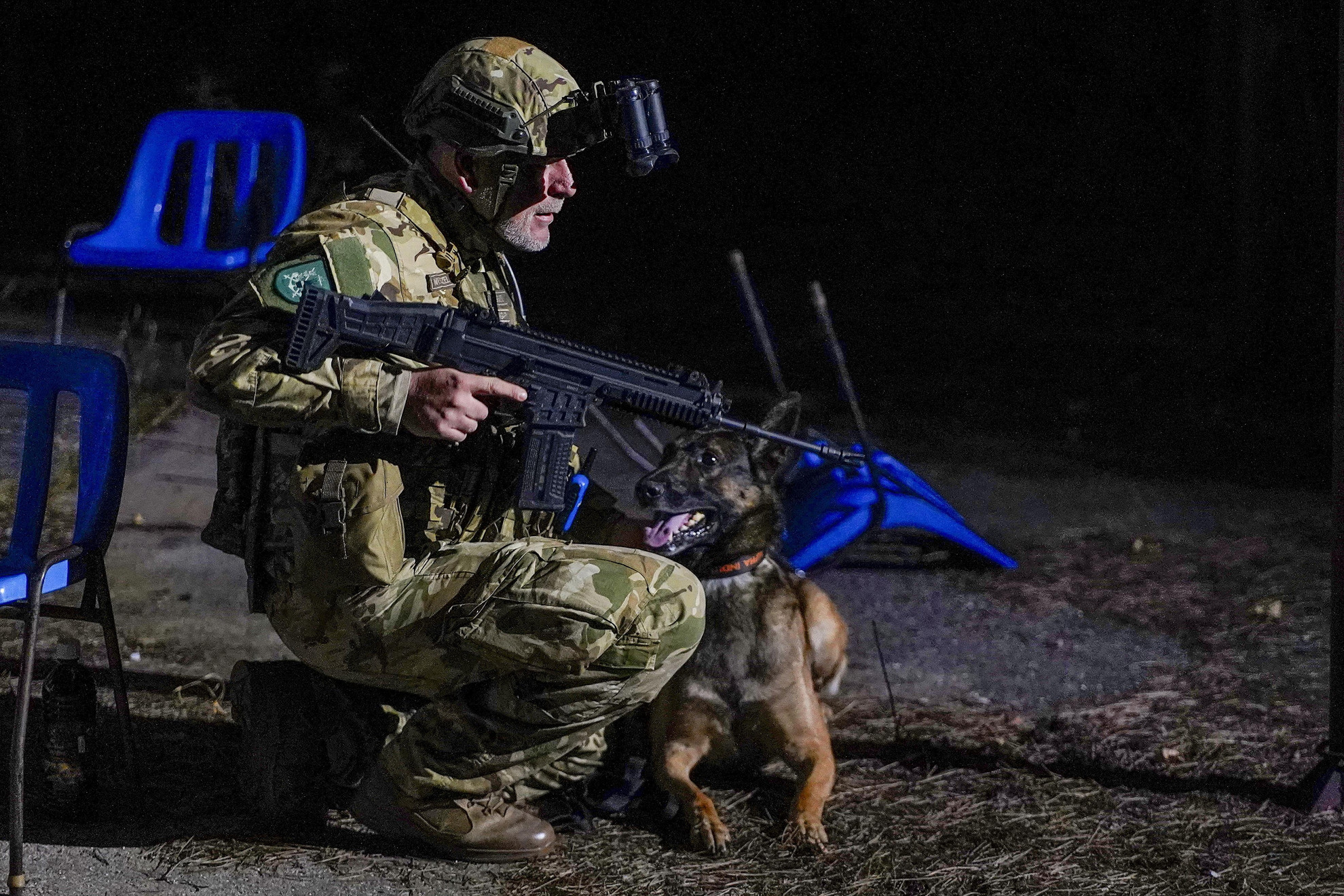 Katona a felderítést segítő robbanóanyag-kereső kutyával az MH 1. Tűzszerész és Folyamőr Ezred katonáinak éjszakai gyakorlatán, amelyen tűzszerészek improvizált robbanóeszközök hatástalanítását végzik egy fiktív merénylet után, speciális körülmények között az újdörögdi gyakorlótéren 2024. október 17-én. A tűzszerészek egy szórakozóhelyen elkövetett, szimulált merénylet után avatkoztak be, felderítettek, majd ártalmatlanítottak különféle házilag gyártott robbanóeszközöket