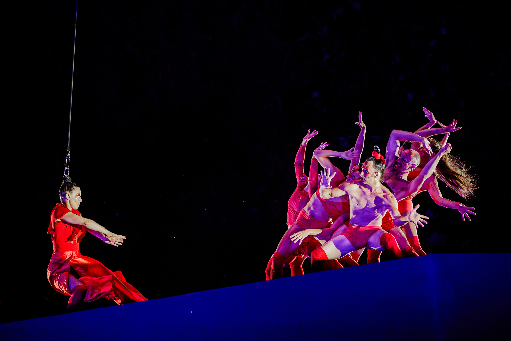 Fotó: Sziget Fesztivál / szigetfestival.com Légibalett előadás a Sziget Fesztiválon: vörös ruhás táncos a levegőben, kortárs mozdulatkompozíció a Sylphes Aerial Ballet produkcióból, látványos esti színpadi show.