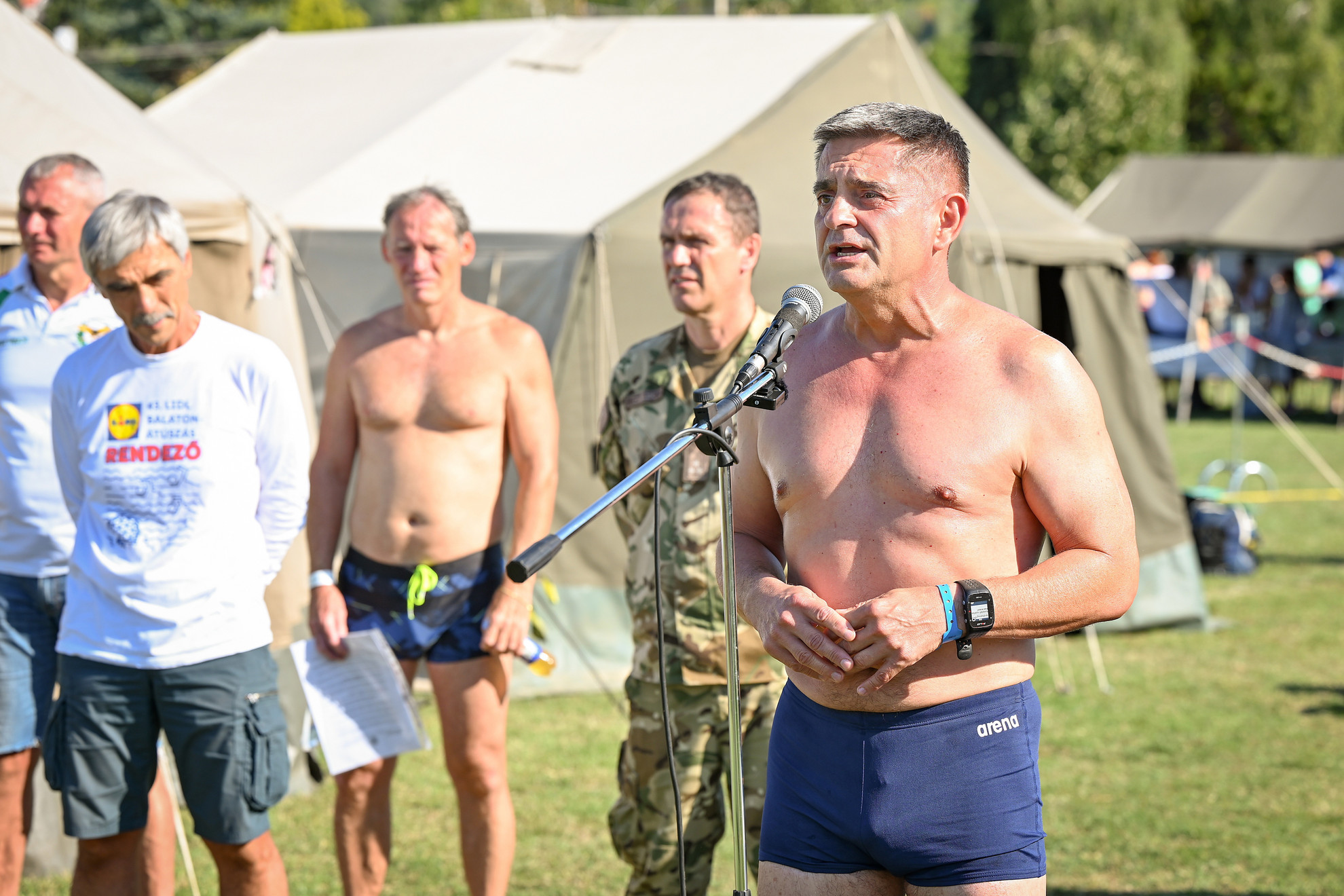 Fotó: MTI/Krizsán Csaba Böröndi Gábor vezérezredes, a Honvéd Vezérkar főnöke (j) bemelegítést tart a Magyar Honvédség katonáiból, honvédelmi alkalmazottaiból és családtagjaikból álló Úszó Erőd csapat rajtja előtt a 43. Lidl Balaton-átúszáson a Révfülöpi szabadstrandon 2025. augusztus 9-én