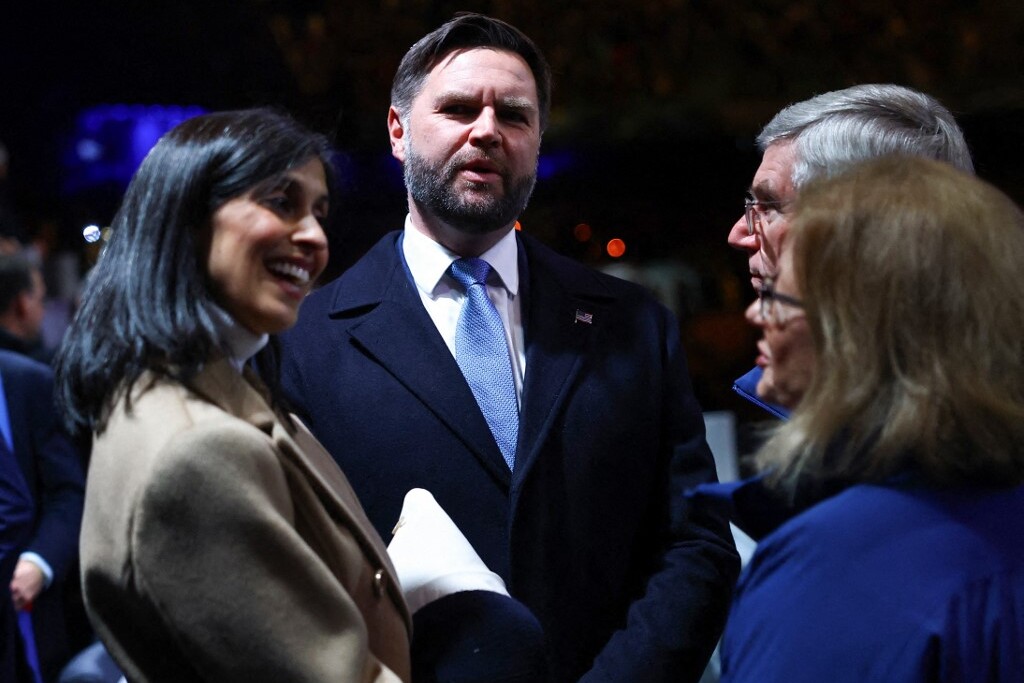 J. D. Vance (b) amerikai alelnök és felesége, Usha Vance, az Egyesült Államok második  Thomas Bach (j) volt NOB-elnökkel élvezték 2026-os milánói-cortinai téli olimpiai játékok megnyitó ünnepségét