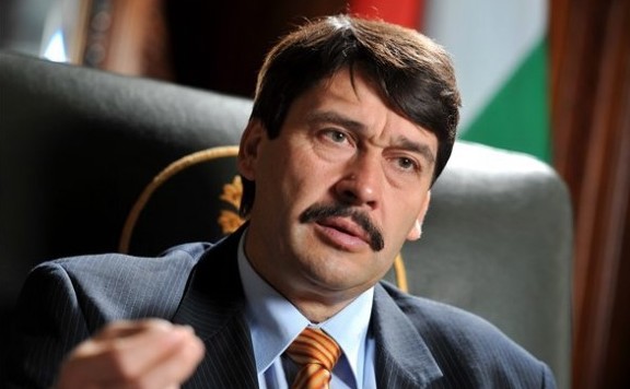 Áder 576 zászló előtt ülve